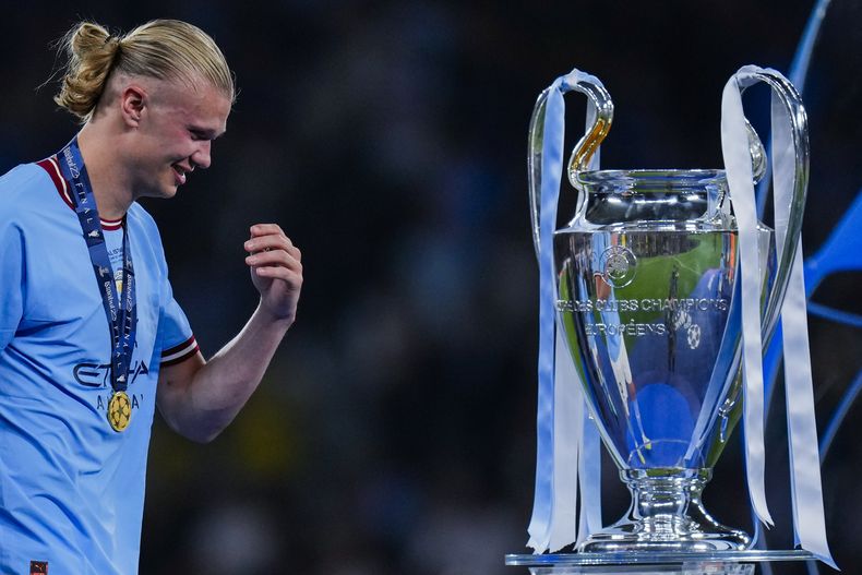 Erling Haaland del Manchester City sonríe al pasar frente al trofeo de la Liga de Campeones tras la victoria 1-0 ante el Inter de Milán en la final, el domingo 11 de junio de 2023, en Estambul. (AP Foto/Manu Fernández)