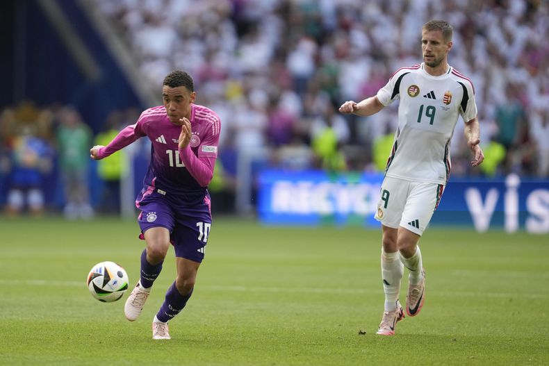 El alemán Jamal Musiala gambetea con el balón superando a Barnabas Varga de Hungría en el Grupo A en la Euro 2024 en Stuttgart, Alemania el 19 de junio del 2024.(AP Foto/Darko Vojinovic)