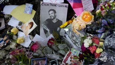 Una fotografía del ex cantante de One Direction, Liam Payne, sentado rodeado de flores y velas mientras los fans se reúnen afuera del hotel donde fue encontrado muerto después de caer desde un balcón en Buenos Aires, Argentina, el jueves 17 de octubre de 2024. (Foto AP/Natacha Pisarenko)