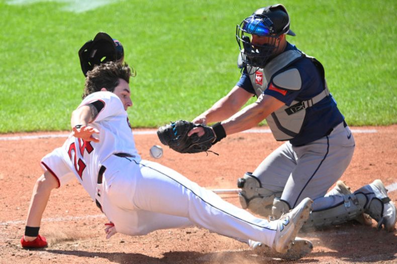 Chase DeLauter, izquierda, de los Guardianes de Cleveland, anota junto a Mitch Garver, de los Marineros de Seattle, durante la octava entrada del juego de béisbol de Grandes Ligas, el domingo 28 de junio de 2026, en Cleveland. (AP Foto/David Richard)