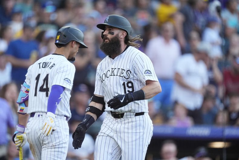 El venezolano Ezequiel Tovar, de los Rockies de Colorado, felicita a Charlie Blackmon, quien conectó un jonrón en el segundo inning del juego ante los Padres de San Diego, el viernes 16 de agosto de 2024 (AP Foto/David Zalubowski)