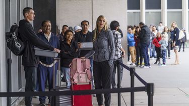 Marni Larsen y su hijo Damon Rasmussen, de Holladay, Utah, esperan en fila para recibir sus pasaportes en Los Ángeles el 14 de junio de 2023. (Foto AP /Damian Dovarganes)
