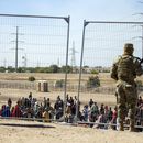 ARCHIVO - Gran cantidad de migrantes aguardan el miércoles 10 de mayo de 2023 junto a la cerca fronteriza para entrar en El Paso, Texas, ante la mirada de miembros de la Guardia Nacional del estado. (AP Foto/Andrés Leighton, archivo)