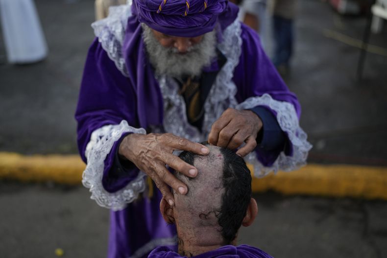 El barbero José Valdespinto corta el cabello de un peregrino, como parte de su penitencia, afuera de la iglesia de San Felipe en honor al Cristo Negro en Portobelo, Panamá, el lunes 21 de octubre de 2024, durante un festival que celebra la icónica estatua que fue encontrada en la orilla del otrora puerto colonial en 1658. (Foto AP/Matías Delacroix)