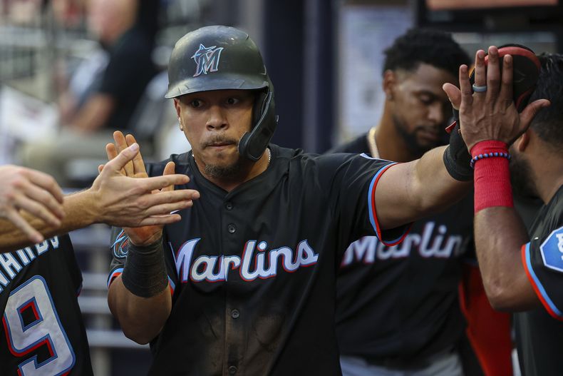 Heriberto Hernandez, de los Marlins de Miami, choca las manos de sus compañeros de equipo en el dugout después de anotar una carrera en la cuarta entrada frente a los Bravos de Atlanta, el viernes 8 de agosto de 2025, en Atlanta. (AP Foto/Colin Hubbard)