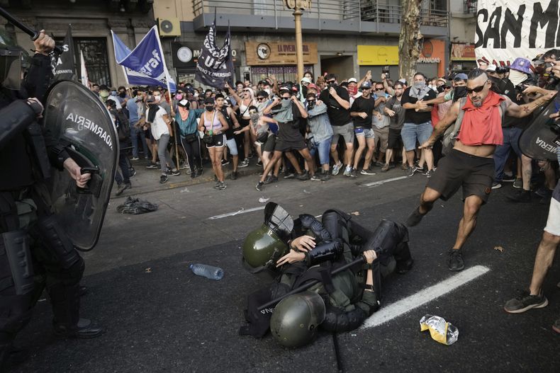 Un manifestante contra el gobierno patea a un policía, caído en el suelo, durante los enfrentamientos a las afueras del Congreso donde los legisladores debaten una reforma impulsada por el presidente argentino, Javier Milei, en Buenos Aires, Argentina, el jueves 1 de febrero de 2024. La propuesta incluye una amplia variedad de medidas económicas, administrativas, penales y medioambientales. (AP Foto/Rodrigo Abd)