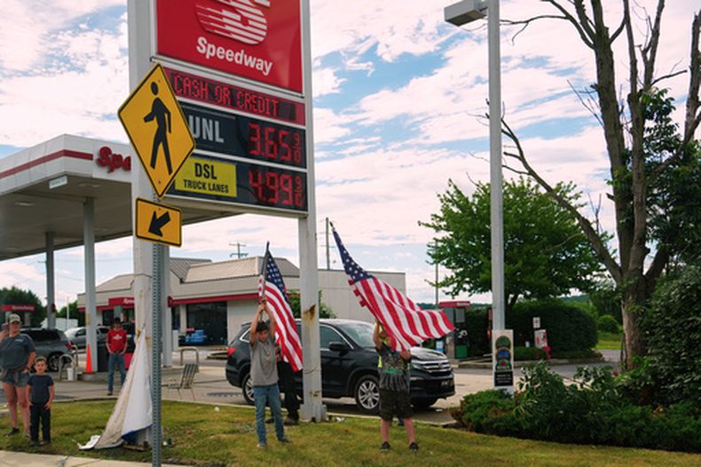 Dos niños ondean banderas de Estados Unidos en una gasolinera mientras la caravana presidencial de Donald Trump pasa frente a ella, el martes 23 de junio de 2026, en Pensilvania. (AP Foto/Julia Demaree Nikhinson)