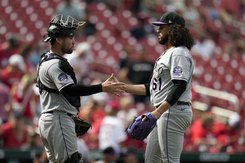 El receptor Austin Wynns y el lanzador Justin Lawrence (61) de los Rockies de Colorado celebran la victoria ante los Cardenales de San Luis, el domingo 6 de agosto de 2023, en San Luis. (AP Foto/Jeff Roberson)