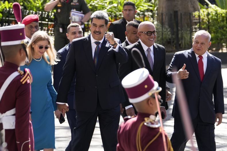 El presidente venezolano, Nicolás Maduro, hace gestos a sus seguidores mientras camina de la mano de su esposa Cilia Flores a su llegada a la Asamblea Nacional para su ceremonia de juramento para un tercer mandato en Caracas, Venezuela, el viernes 10 de enero de 2025. (AP Foto/Matías Delacroix)
