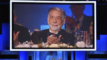 El cineasta Francis Ford Coppola aparece en la pantalla mientras los actores Al Pacino, a la izquierda, y Robert De Niro, hablan sobre su trayectoria durante un tributo a la trayectoria de Coppola en la 50ma entrega de los premios AFI, el sábado 26 de abril de 2025, en Los Ángeles. (AP Foto/Chris Pizzello)