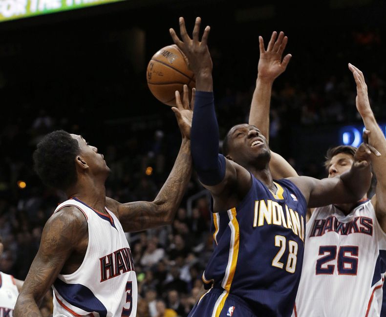Ian Mahinmi (28), de los Pacers de Indiana, intenta tomar un rebote entre Kyle Korver (26) y Louis Williams, de los Hawks de Atlanta, en la primera mitad del juego del mi&eacute;rcoles 8 de enero de 2014, en Atlanta, (Foto AP/John Bazemore)