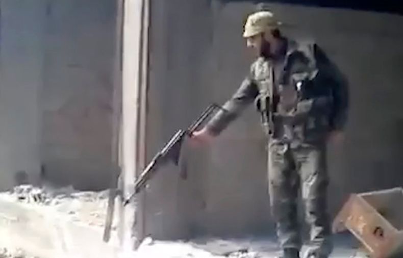 ARCHIVO - En esta imagen, tomada de un video de 2013, se muestra a un soldado sirio disparando a una zanja llena de cuerpos, en el vecindario de Tadamon, en Damasco, Siria. (AP Foto, archivo)