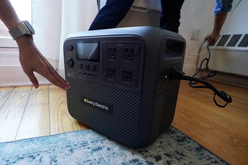 Sonam Velani y Yan Sim conectan una batería de Every Electric para alimentar su aire acondicionado como parte de un programa piloto con la empresa de electricidad de la ciudad Con Edison para reducir la presión sobre la red eléctrica, el lunes 27 de abril de 2026, en el distrito de Brooklyn, en Nueva York. (AP Foto/Alyssa Goodman)