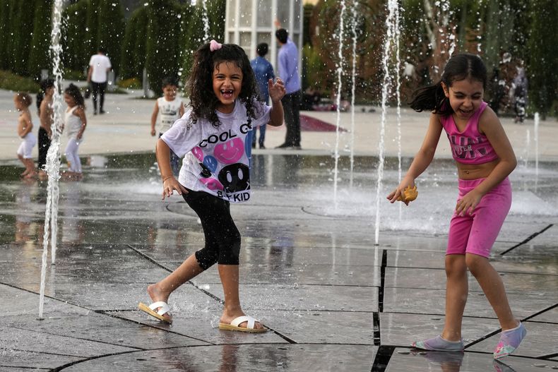 Unas niñas juegan en una fuente en el parque Ebrahim mientras las temperaturas en Teherán alcanzan los 38 C (100 F) en Irán, el 1 de agosto de 2023. (AP Foto/Vahid Salemi)
