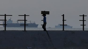 Un niño palestino lleva una caja de ayuda en la carretera de la playa del campamento de refugiados de Nusseirat, en el centro de la Franja de Gaza, el sábado 18 de mayo de 2024, luego de que la gente se abalanzara sobre camiones cargados de ayuda humanitaria introducida a través de un nuevo muelle construido por Estados Unidos. (AP Foto/Saher Alghorra)
