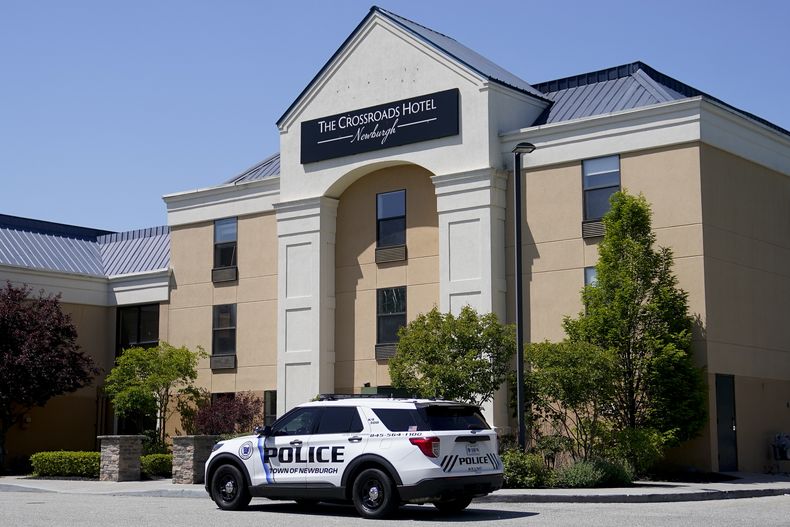 ARCHIVO - Un vehículo policial estacionado afuera del hotel The Crossroads, adonde llegaron dos autobuses con migrantes el 11 de mayo d 2023. La fundadora de una organización sin ánimo de lucro ha sido acusada de fabricar una historia sobre que veteranos del ejército sin hogar habían sido desalojados del hotel para hacerle espacio a migrantes (AP Foto/John Minchillo, Archivo)