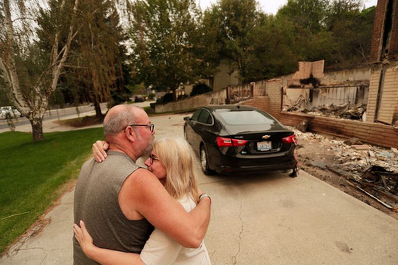 Allen Sather y su esposa Kimberley se abrazan ante la vivienda que arriendan en W. Indian Trail Road, que ardió en un incendio forestal en Spokane, Washington, el domingo 2 de agosto de 2026. (AP Foto/Young Kwak)