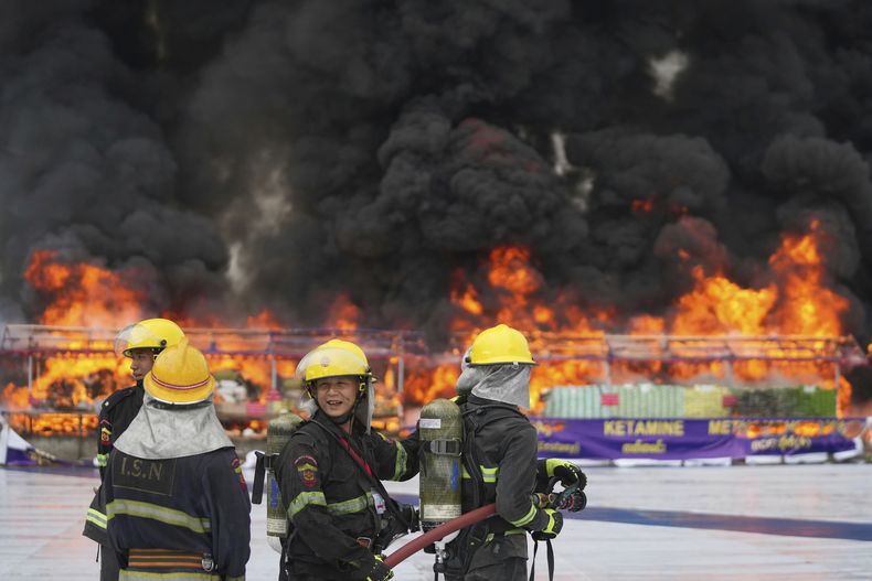 Bomberos, junto a una enorme hoguera donde se destruyen drogas ilegales, en un acto para conmemorar el Día Internacional de la Lucha contra el Uso Indebido y el Tráfico Ilícito de Drogas, a las afueras de Rangún, Myanmar, el 26 de junio de 2025. (AP Foto/Thein Zaw)