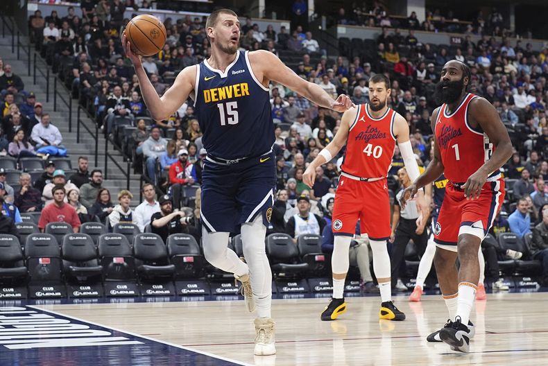 Nikola Jokic, izquierda, de los Nuggets de Denver, busca pasar el balón, mientras Ivica Zubac (40) y James Harden (1), de los Clippers de Los Ángeles, defienden durante la primera mitad del juego de baloncesto de la NBA, el viernes 13 de diciembre de 2024, en Denver. (AP Foto/David Zalubowski)