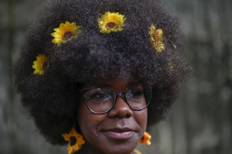 Una mujer con girasoles en el pelo espera para caminar por la pasarela en un desfile de moda de peinados afro en La Habana, Cuba, el sábado 31 de agosto de 2024. (Foto AP/Ramón Espinosa)