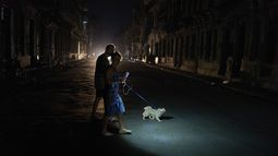 La gente enciende una linterna mientras cruza una calle con su perro durante un apagón en La Habana, el miércoles 10 de septiembre de 2025. (AP Foto/Ramón Espinosa)
