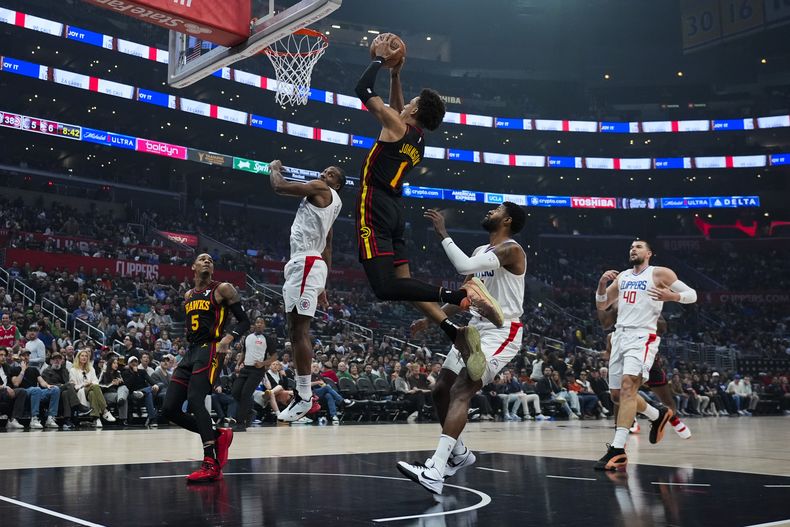Jalen Johnson (1), de los Hawks de Atlanta, se alista para encestar superando el brinco de Kawhi Leonard (2) y por delante de Paul George (13), de los Clippers de Los Ángeles, durante la primera mitad del juego de baloncesto de la NBA, en Los Ángeles, el domingo 17 de marzo de 2024. (AP Foto/Ashley Landis)
