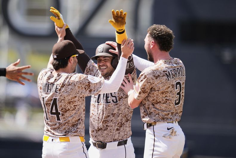 José Iglesias, centro, de los Padres de San Diego, celebra con sus compañeros de equipo Tyler Wade, izquierda, y Jackson Merrill después de producir una carrera con una rola de decisión del defensivo para derrotar a los Reales de Kansas City durante la novena entrada del juego de béisbol de Grandes Ligas, el domingo 22 de junio de 2025, en San Diego. Los Padres ganaron 3-2. (AP Foto/Gregory Bull)