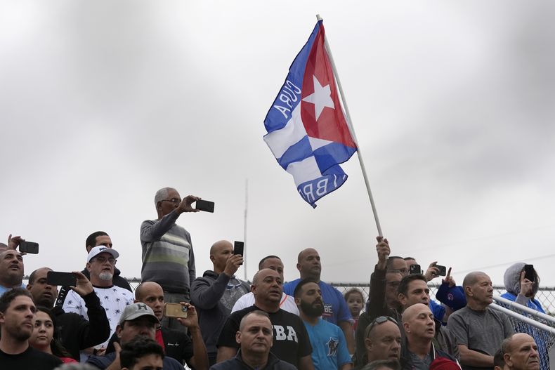 Fanáticos cantan el himno nacional de Cuba antes de un juego de exhibición del equipo denominado Federación Profesional Cubana de Beisbol (FEPCUBE) ante el Miami Dade College, el 17 de enero de 2024 (AP Foto/Wilfredo Lee)