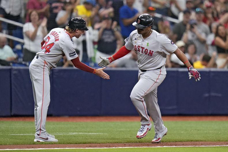 El dominicano de los Medias Rojas de Boston, Rafael Devers celebra con el entrenador de tercera base Kyle Hudson (84) luego de su cuadrangular de dos carreras ante el abridor de los Rays de Tampa Bay Taj Bradley durante la cuarta entrada del juego de béisbol, el lunes 20 de mayo de 2024, en San Petersburgo, Florida. (AP Foto/Chris OMeara)