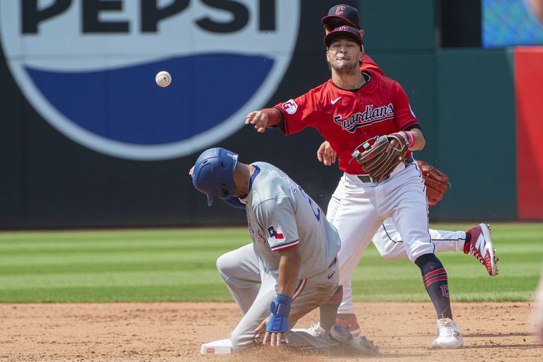 Tyler Freeman, derecha, de los Guardianes de Cleveland, retira a Marcus Semien, izquierda, de los Rangers de Texas, en segunda base durante la sexta entrada del juego de béisbol en Cleveland, el domingo 25 de agosto de 2024. (AP Foto/Phil Long)