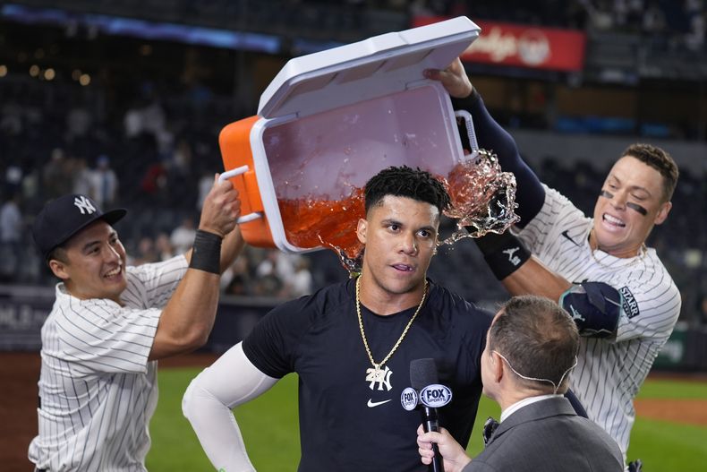 Anthony Volpe (izquierda) y Aaron Judge vacían la hielera encima del dominicano Juan Soto, su compañero de los Yankees de Nueva York, tras la victoria sobre los Medias Rojas de Boston, el jueves 12 de septiembre de 2024 (AP Foto/Seth Wenig)