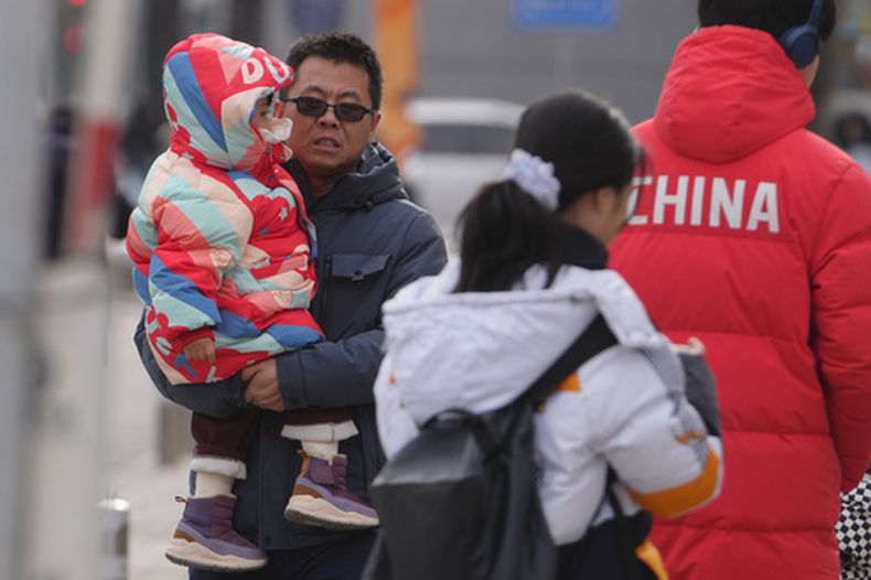 Un hombre lleva a un niño pequeño por una calle de Beijing, el lunes 19 de enero de 2026. (Foto AP/Andy Wong)