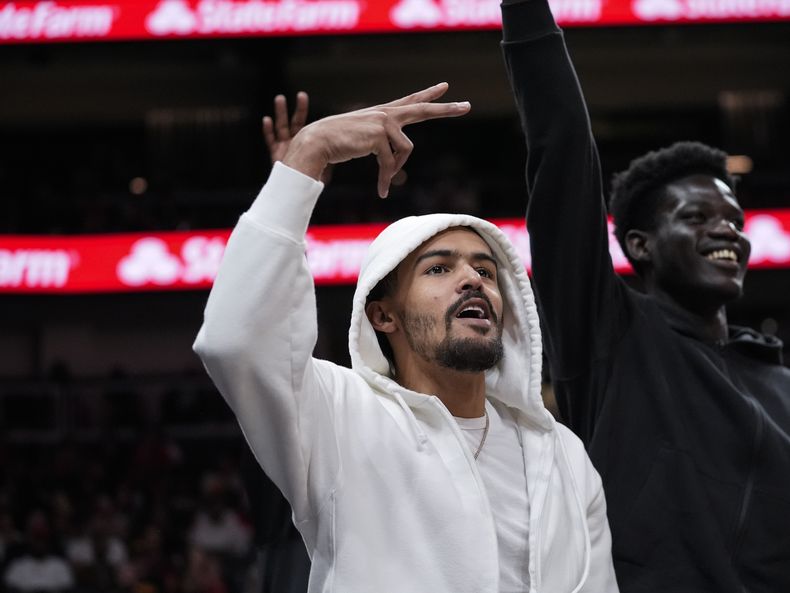 El lesionado Trae Young, de los Hawks de Atlanta, reacciona a una canasta de su equipo durante la primera mitad del juego de baloncesto de la NBA en contra de los Trail Blazers de Portland, el miércoles 27 de marzo de 2024, en Atlanta. (AP Foto/John Bazemore)