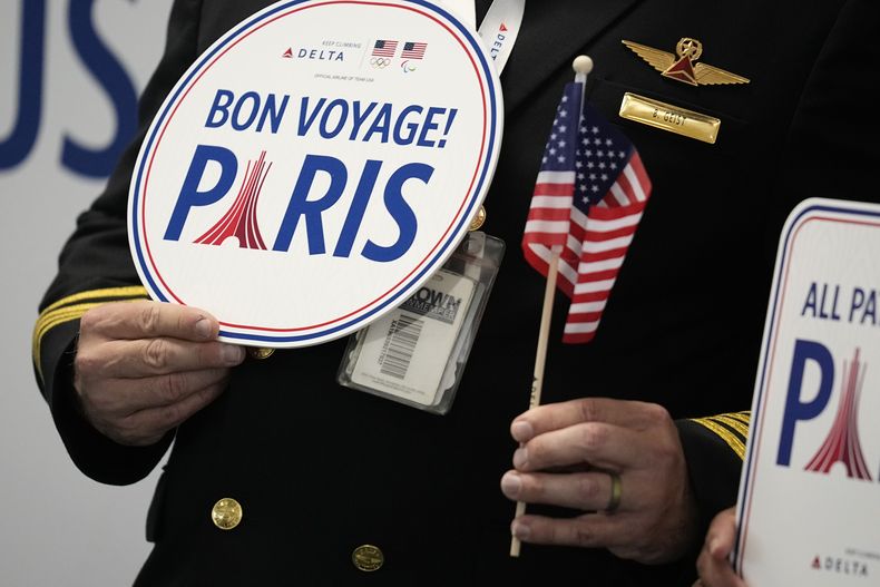 Un piloto sostiene un cartel en el que desea buen viaje a algunos deportistas estadounidenses que se aprestan a partir de Atlanta hacia los Juegos Olímpicos de París, el miércoles 17 de julio de 2024 (AP Foto/Brynn Anderson)