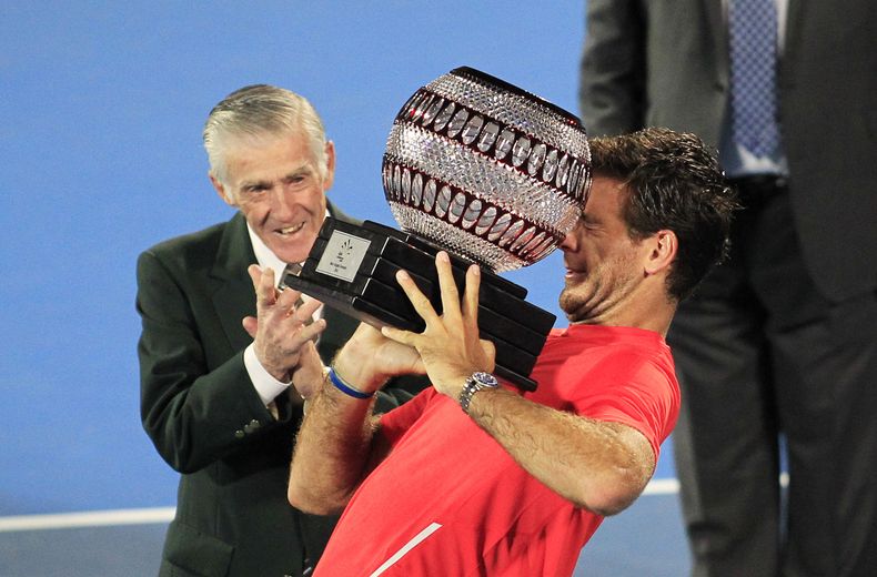 El argentino Juan Mart&iacute;n Del Potro intenta levantar su trofeo de campe&oacute;n del torneo de Sydney ante la mirada del legendario tenista Ken Rosewall el s&aacute;bado 11 de enro de 2013. (AP Foto/Daniel Munoz)