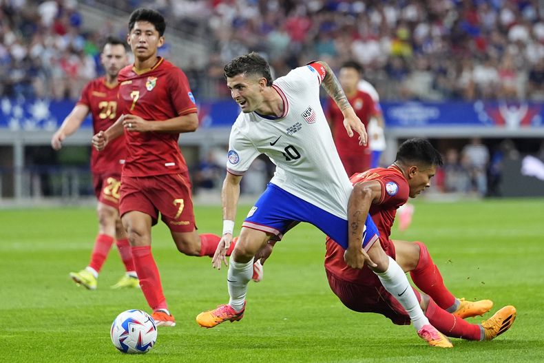 El delantero estadounidense Christian Pulisic es sujetado por el boliviano Héctor Cuéllar en el partido por el Grupo C de la Copa América, el domingo 23 de junio de 2024, en Arlington, Texas. (AP Foto/Julio Cortez)