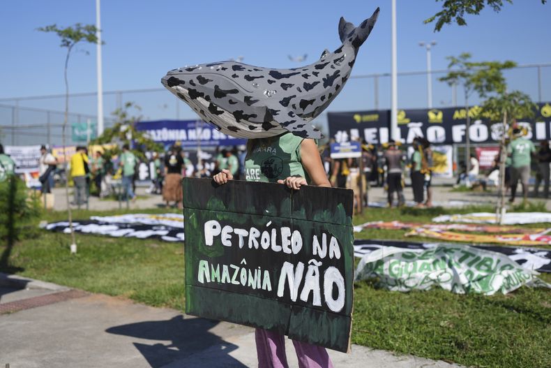 Un manifestante con una ballena hecha de papel en la cabeza sostiene un letrero con la frase No al petróleo en la Amazonía en portugués, el martes 17 de junio de 2025 en Río de Janeiro, en protesta contra la subasta de sitios petroleros. (AP Foto/Silvia Izquierdo