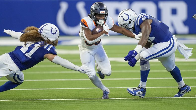 El running back Jaleel McLaughlin (38), de los Broncos de Denver, lleva el balón y busca eludir al linebacker Grant Stuard (41) y al defensive end Titus Leo (91), de los Colts de Indianápolis, durante el tercer cuarto del juego de pretemporada de la NFL, el domingo 11 de agosto de 2024, en Westfield, Indiana. (AP Foto/AJ Mast)