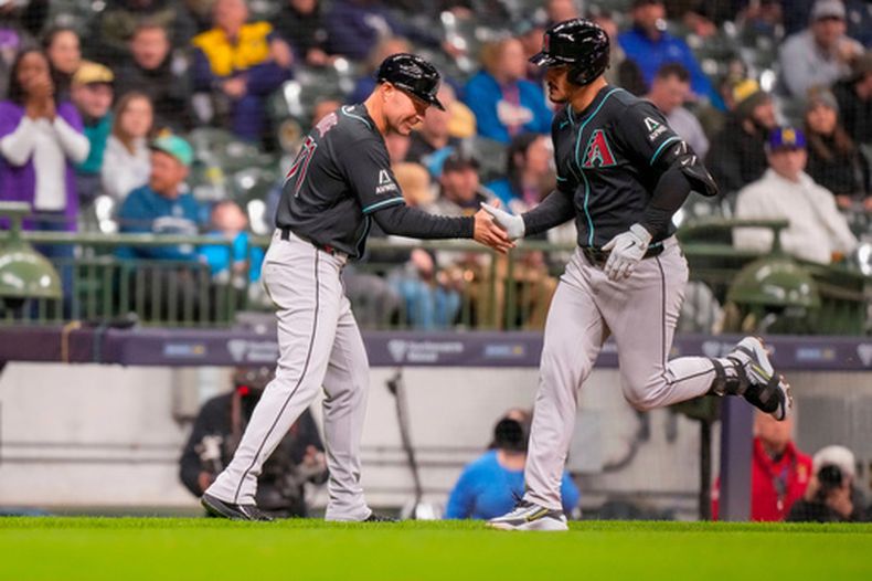 Nolan Arenado, de los Diamondbacks de Arizona, recorre las bases tras un jonrón de dos carreras, recibiendo un saludo del entrenador de tercera base J.R. House durante la cuarta entrada del partido de béisbol contra los Cerveceros de Milwaukee el miércoles 29 de abril de 2026 en Milwaukee. (Foto AP/Andy Manis)