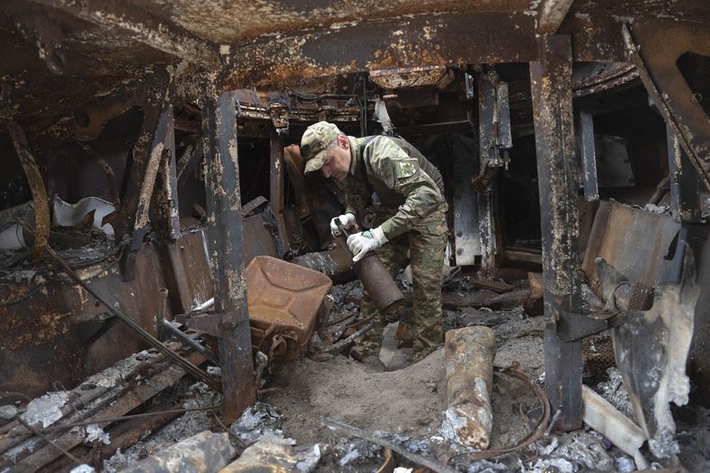 Un zapador inspecciona un vehículo ruso dañado, que había sido instalado como símbolo de la guerra en el centro de Kiev, Ucrania, el 15 de junio de 2023. (AP Foto/Efrem Lukatsky)