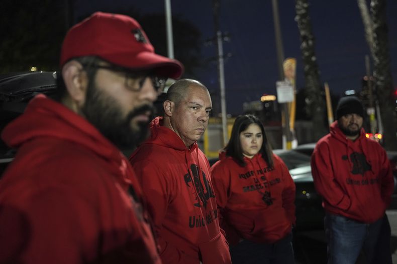 Ron Gochez, segundo de izquierda a derecha, un profesor voluntario para Unión del Barrio, una organización que defiende los derechos de los inmigrantes, escucha a otros voluntarios reunidos en un estacionamiento antes de rastrear operativos de agentes del Servicio de Control de Inmigración y Aduanas (ICE) en Los Ángeles el jueves 27 de febrero de 2025. (AP Foto/Jae C. Hong)