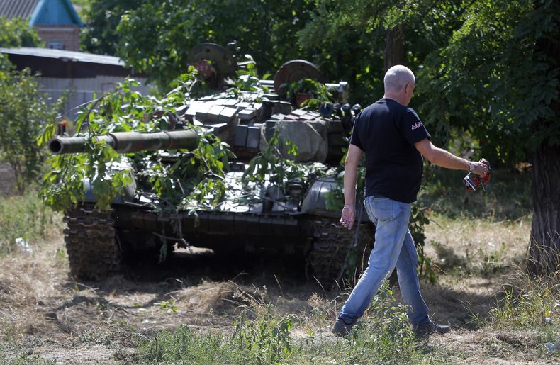 Un hombre pasa al lado de un tanque camuflado en el poblado de Novoazovsk, en el este de Ucrania, el viernes 29 de agosto de 2014. (Foto AP/Sergei Grits)