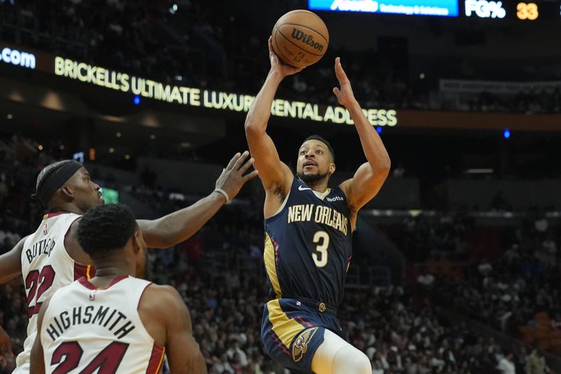 CJ McCollum (3), de los Pelicans de Nueva Orleans, se alista para anotar sobre Jimmy Butler (22) y Haywood Highsmith (24), del Heat de Miami, durante la primera mitad del juego de baloncesto de la NBA, el viernes 22 de marzo de 2024, en Miami. (AP Foto/Marta Lavandier)