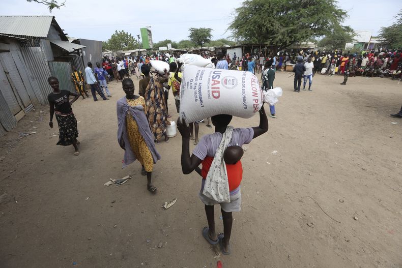 Refugiados cargan alimentos en un centro de distribución operado por el Programa Mundial de Alimentos de la ONU en el campamento de refugiados de Kakuma, en Turkana, Kenia, el martes 3 de junio de 2025. (AP Foto/Andrew Kasuku)