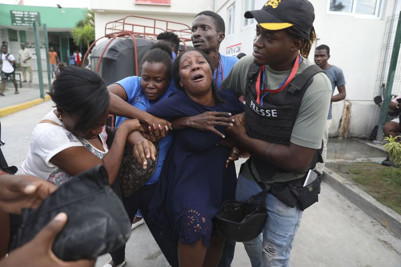 La esposa de un periodista, que fue baleado durante un ataque de pandillas en el Hospital General de Puerto Príncipe, Haití, llora mientras llega una ambulancia con el cuerpo de su esposo, el martes 24 de diciembre de 2024. (AP Foto/Odelyn Joseph)