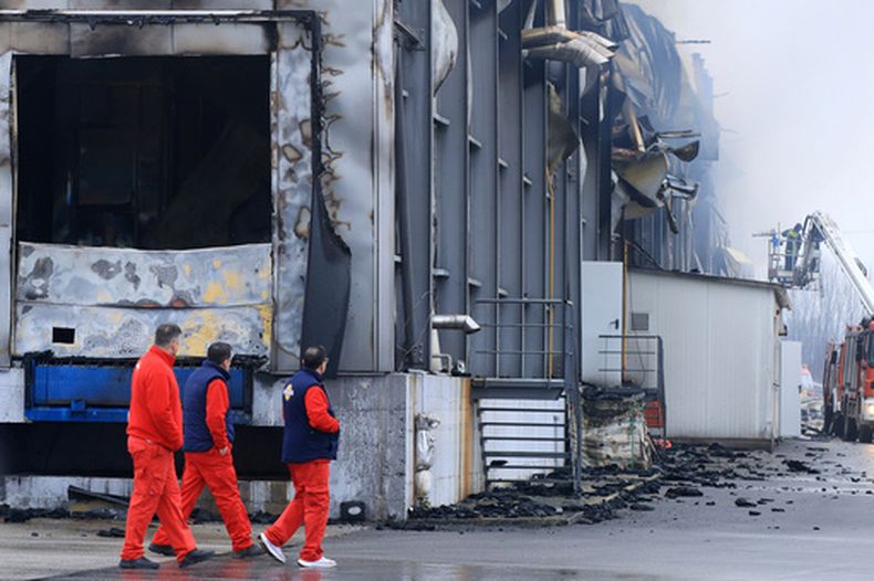 Trabajadores pasan junto a un edificio quemado tras una explosión y un incendio en una fábrica de galletas en Trikala, en el centro de Grecia, el lunes 26 de enero de 2026. (George Kidonas/InTime News via AP)