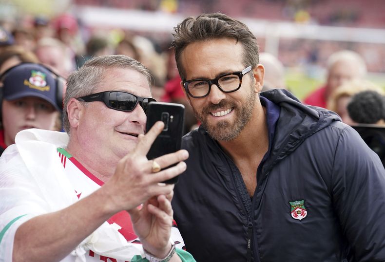 Ryan Reynolds, codueño del Wrexham, posa con aficionados previo al partido contra Boreham Wood en la National League, el sábado 22 de abril de 2023. (Martin Rickett/PA vía AP)