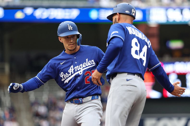 Tommy Edman, de los Dodgers de Los Ángeles, celebra su sencillo productor de una carrera junto a Chris Woodward durante la primera entrada de un partido de béisbol contra los Mellizos de Minnesota, el martes 23 de junio de 2026, en Minneapolis. (Foto AP/Matt Krohn)