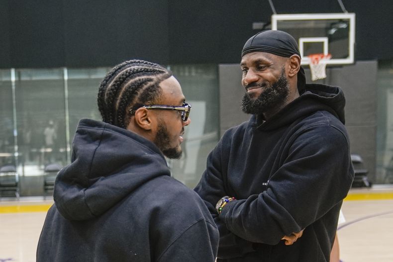 El recién seleccionado de los Lakers de Los Ángeles Bronny James habla con su padre LeBron James al llegar a la conferencia de prensa del equipo el martes 2 de julio del 2024. (AP Foto/Damian Dovarganes)