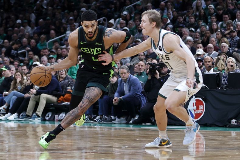 Jayson Tatum (0), de los Celtics de Boston, avanza con el balón dejando atrás a AJ Green (20), de los Bucks de Milwaukee, durante la primera mitad del juego de baloncesto de la NBA, el viernes 6 de diciembre de 2024, en Boston. (AP Foto/Mary Schwalm)